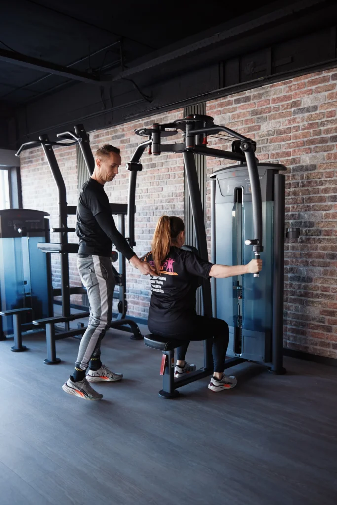 Michael begeleidt een lid van de sportschool in haar oefeningen in de Vrije Fitness ruimte van Building You in Etten-Leur