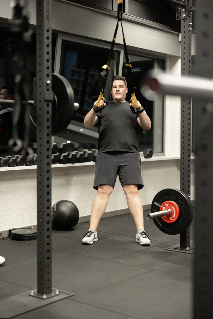 Man traint met TRX-banden en een stang in het rack bij Building You in Etten-Leur