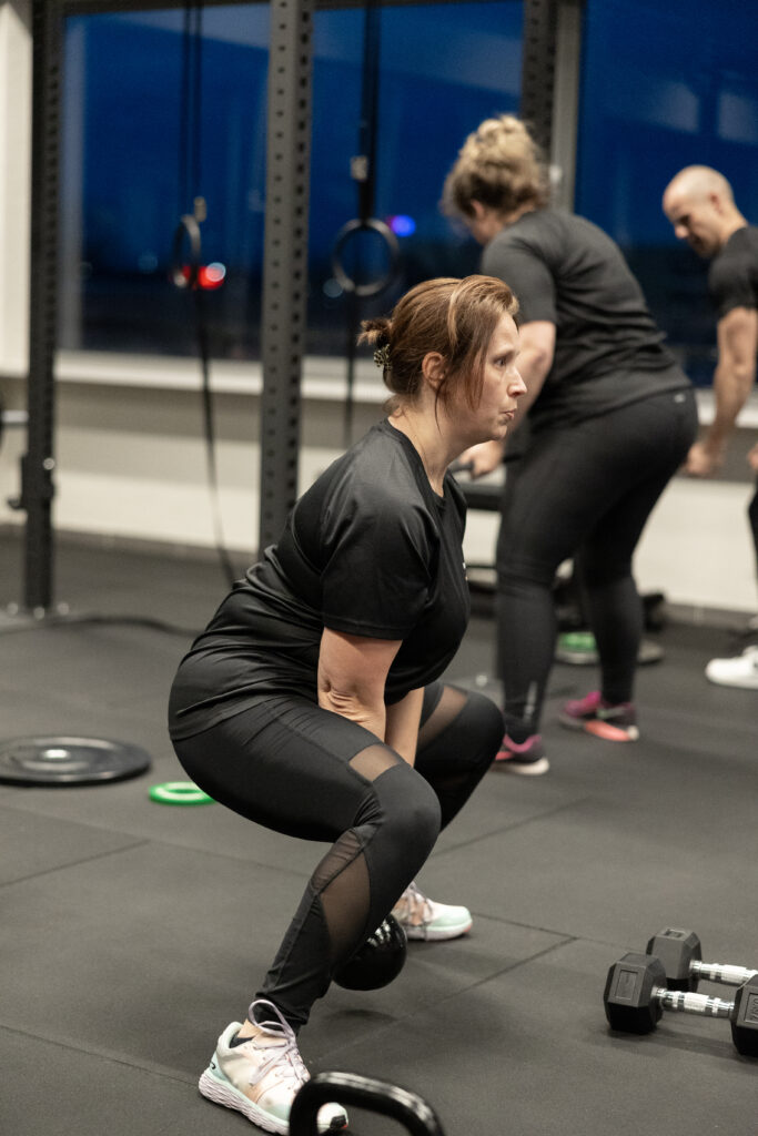 Vrouw doet een squat bij een kettlebell tijdens groepstraining bij Building You in Etten-Leur