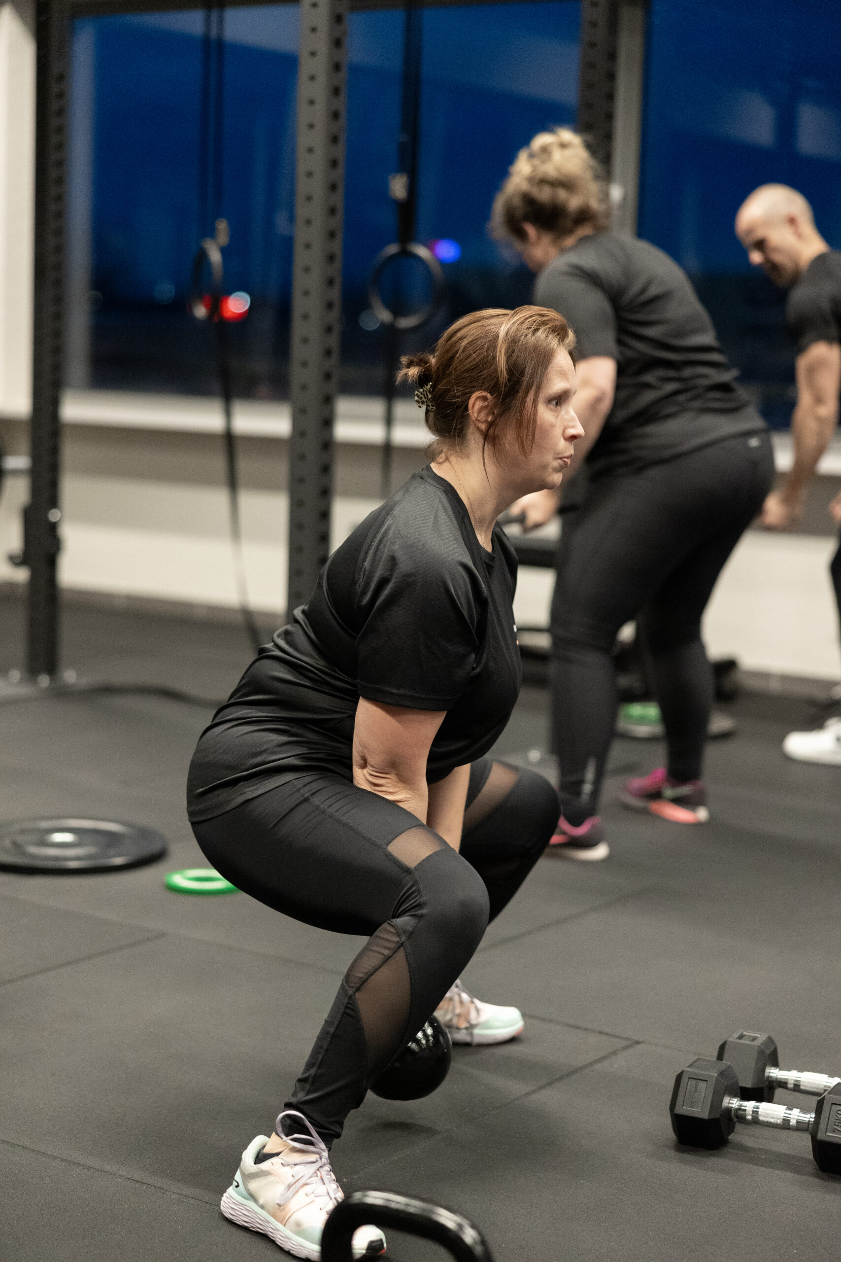 Vrouw doet een squat bij een kettlebell tijdens groepstraining bij Building You in Etten-Leur