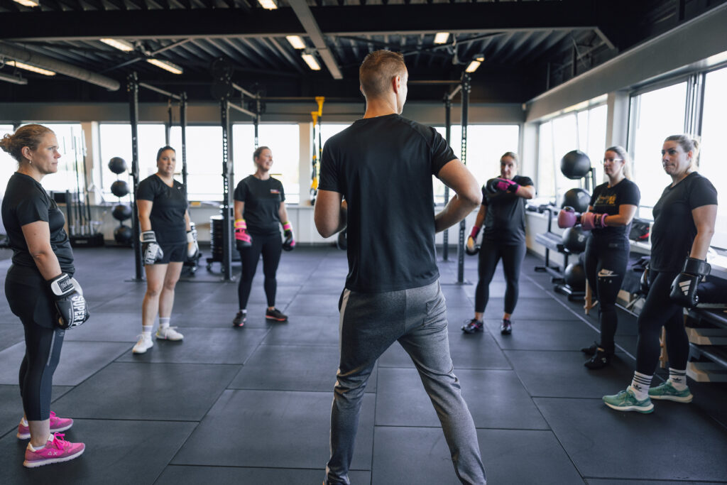 Deelnemers met bokshandschoenen luisteren naar de coach tijdens bokstraining bij Building You in Etten-Leur