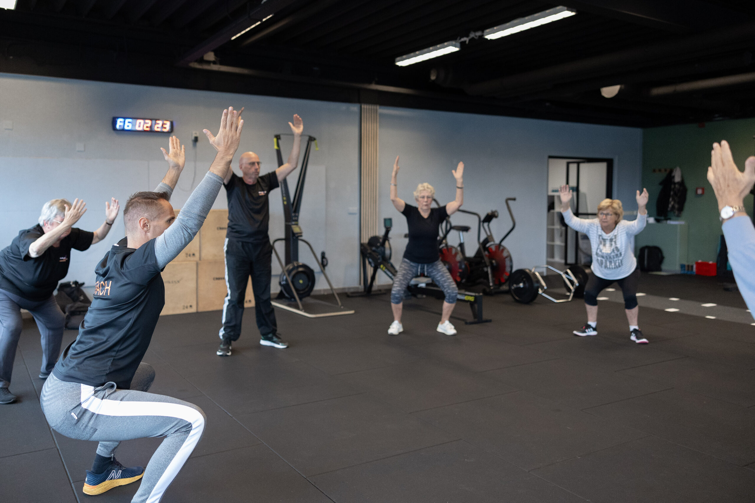 Senioren doen squats met de armen omhoog tijdens een ZilverFit-groepsles bij Building You in Etten-Leur