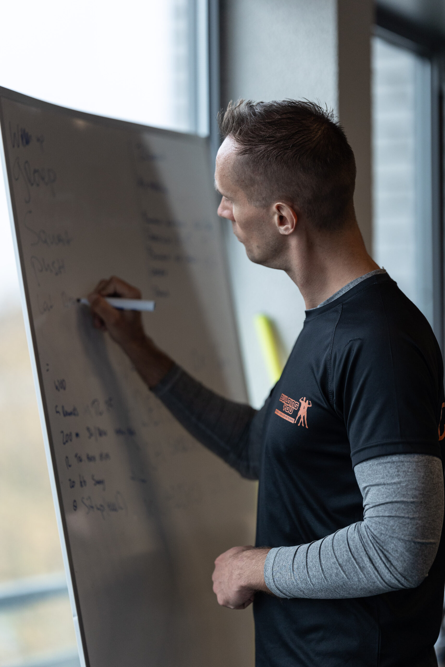 Coach schrijft de training op het bord voor een groepsles bij Building You in Etten-Leur